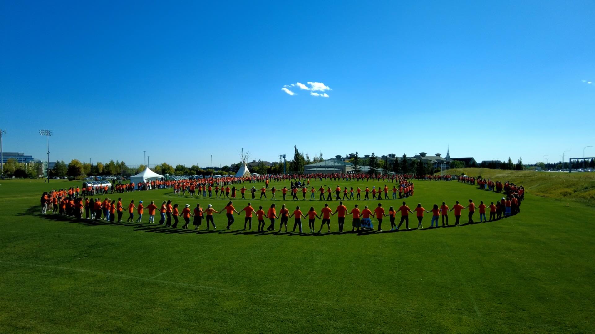 People holding hands in a spiderweb formation on a soccer field